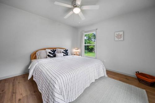 una camera da letto bianca con un letto e un ventilatore a soffitto di Midtown Modern Cottage a Tyler