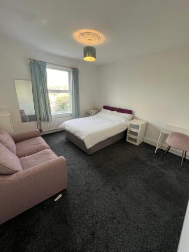 sypialnia z łóżkiem, kanapą i oknem w obiekcie Sweet Homes w Londynie