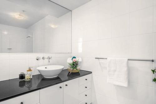 Baño blanco con lavabo y espejo en A Modern Apt City Views Next to Darling Harbour, en Sídney