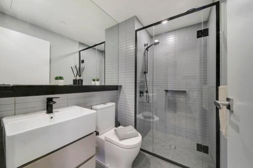La salle de bains est pourvue de toilettes, d'un lavabo et d'une douche. dans l'établissement A Comfy 2BR Apt 5-Min Walk To Melbourne Central, à Melbourne