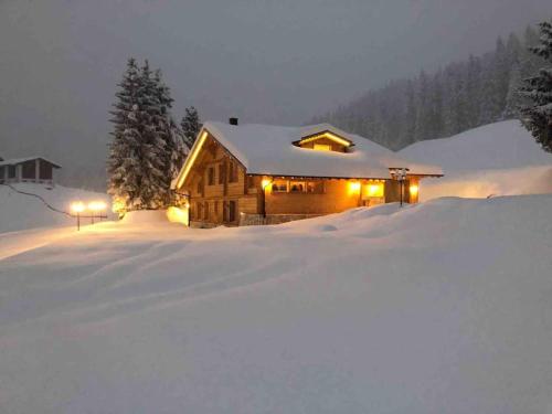 a log cabin in the snow with lights on at Chalet Riedhuus in Davos Wolfgang