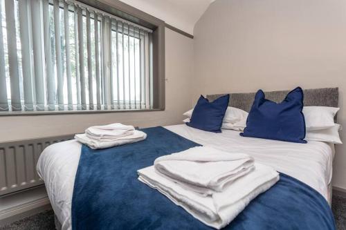 uma cama com almofadas azuis e toalhas brancas em Stylish House - Close to City Centre - Free Parking, Super-Fast Wifi and Smart TVs by Yoko Property em Middlesbrough