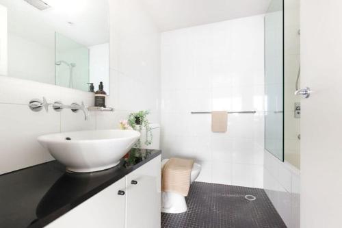 a white bathroom with a sink and a shower at A Comfy 2BR Apt Harbour View FREE Parking in Sydney