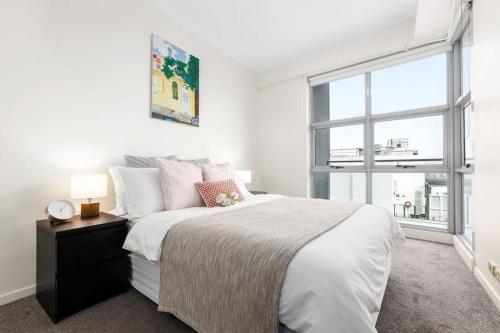 a white bedroom with a large bed and a window at A Comfy 2BR Apt Harbour View FREE Parking in Sydney