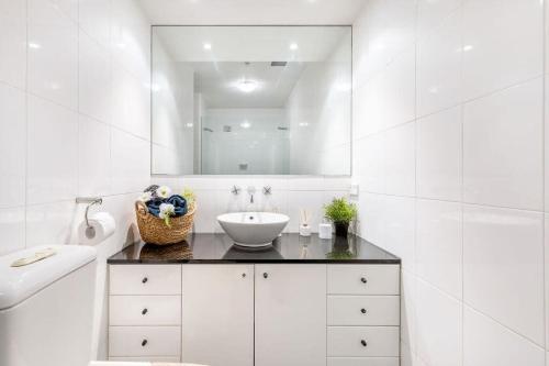 a white bathroom with a sink and a mirror at A Cozy Studio CBD Next to Darling Harbour in Sydney