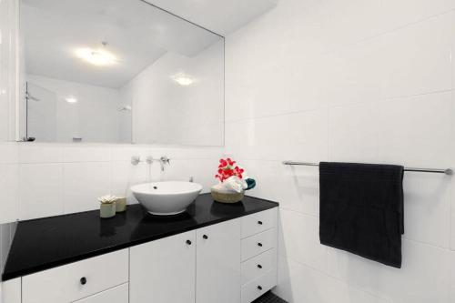uma casa de banho branca com um lavatório e um espelho em A Stylish Apt City Views Next To Darling Harbour em Sydney