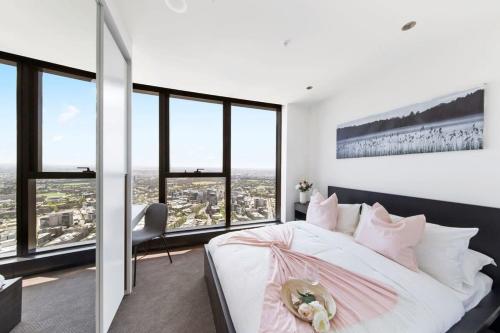 a bedroom with a large white bed and large windows at A Cozy 3BR Apt with Panoramic Views FREE Parking in Melbourne