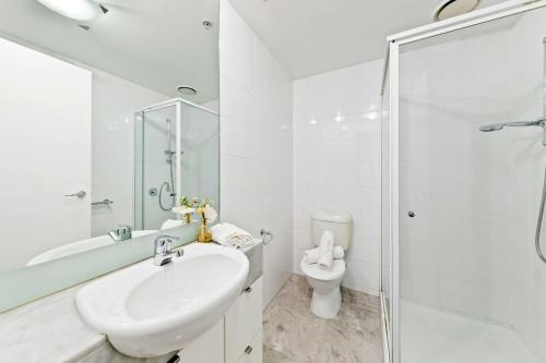 a white bathroom with a sink and a toilet at A Large 2BR Apt Near Crown Sleeps 8 FREE Parking in Melbourne