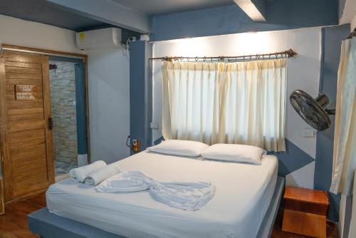 a bedroom with a bed with white sheets and a window at La Playita Isla Fuerte in Isla Fuerte