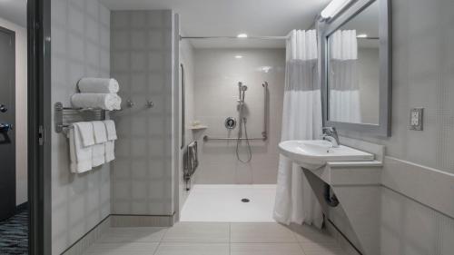 La salle de bains blanche est pourvue d'une douche et d'un lavabo. dans l'établissement Holiday Inn Winnipeg - Airport West, an IHG Hotel, à Winnipeg