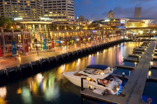 a boat is docked at a marina at night at A Comfy 2BR Apt Right Next to Darling Harbour in Sydney