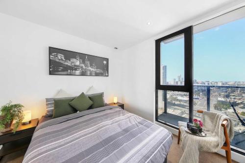 a bedroom with a bed and a large window at A Stylish 2BR Apt with City Views in Southbank in Melbourne