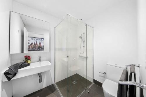a white bathroom with a sink and a shower at A Stylish 2BR Apt with City Views in Southbank in Melbourne