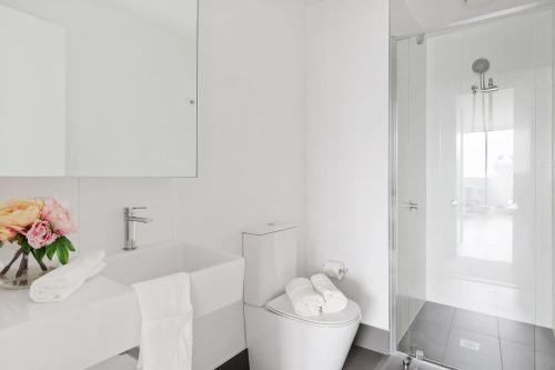 a white bathroom with a toilet and a sink at An Amazing 2BR Apt with City Views in Southbank in Melbourne