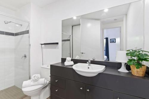 a bathroom with a sink and a toilet and a mirror at A Spacious 2BR Apt with a Courtyard & FREE Parking in Melbourne