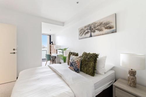 メルボルンにあるA Lux 2BR Apt Next to Melbourne Uni FREE Parkingの白いベッドルーム(ベッド1台、ランプ付)