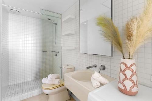 een badkamer met een toilet en een vaas met een plant bij A Lux 2BR Apt Next to Melbourne Uni FREE Parking in Melbourne