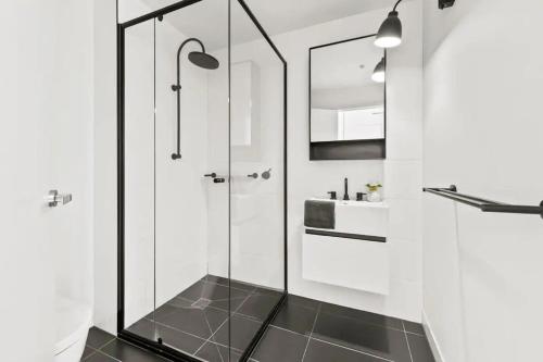 a bathroom with a glass shower and a sink at Chic & Comfy Apartment on Bourke St Near Chinatown in Melbourne