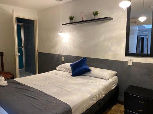 a bedroom with a bed with a blue pillow on it at hostal casa prado in in Medellín