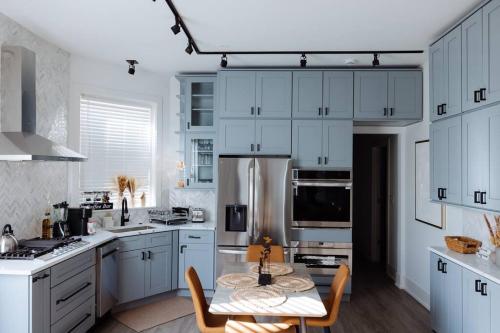 a kitchen with white cabinets and a table with chairs at The Brown House - A luxurious UChicago Campus stay in Chicago