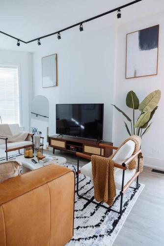 a living room with a couch and a tv at The Brown House - A luxurious UChicago Campus stay in Chicago