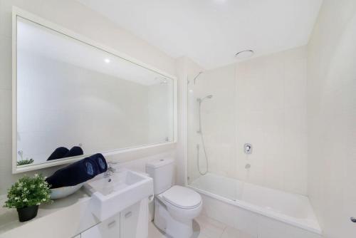 a white bathroom with a toilet and a bath tub at A Stylish 2BR Apt Next to Crown with FREE Parking in Melbourne