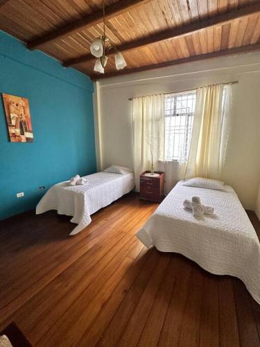 a bedroom with two beds and a wooden floor at Casa Comoda Centrica con Garage in Puyo