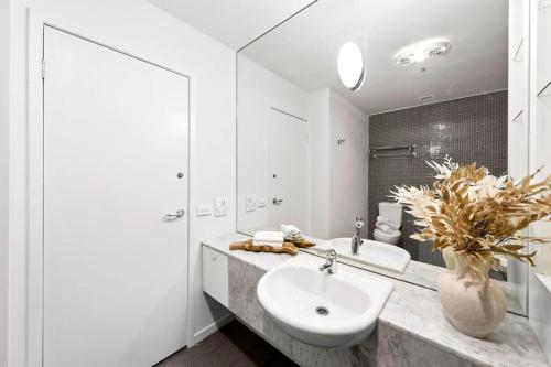a white bathroom with a sink and a mirror at A Chic Apartment on Bourke St Near Chinatown in Melbourne