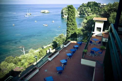 a balcony with blue chairs and a view of the water at Bay Palace Mazzarò in Taormina