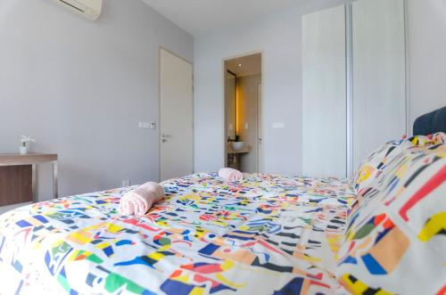 a baby laying on a bed with a colorful comforter at Lux 3BR Suite Puteri Harbour Near Legoland & Hello Kitty in Nusajaya