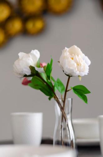 two white flowers in a glass vase on a table at Lux 3BR Suite Puteri Harbour Near Legoland & Hello Kitty in Nusajaya