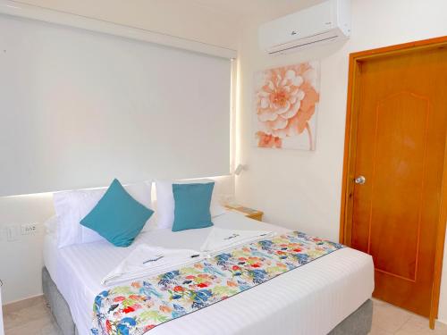a white bed with blue pillows in a room at Hotel Grand Caribe in San Andrés