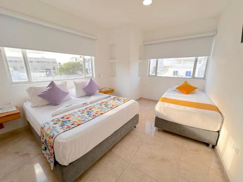 a bedroom with two beds and two windows at Hotel Grand Caribe in San Andrés