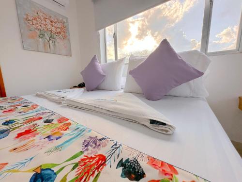 a bedroom with a bed with white sheets and pillows at Hotel Grand Caribe in San Andrés