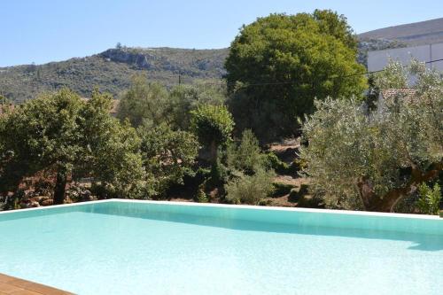 een zwembad met bomen en een berg op de achtergrond bij Casa dos Aromas - Nature Tourism in Alvados