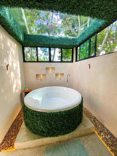 a large bath tub in a room with windows at Villas Zamna - Jungle Villas in Cozumel