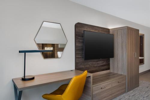 a room with a desk with a tv and a yellow chair at Holiday Inn Express Hotel & Suites Terre Haute by IHG in Terre Haute
