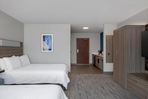 a hotel room with two beds and a flat screen tv at Holiday Inn Express Hotel & Suites Terre Haute by IHG in Terre Haute