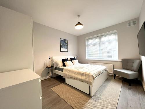 een slaapkamer met een bed, een stoel en een raam bij ArtLounge-2 bed garden Free parking in Enfield Lock