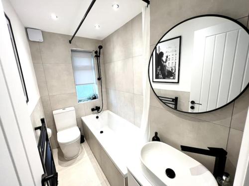 een badkamer met een wastafel, een toilet en een spiegel bij ArtLounge-2 bed garden Free parking in Enfield Lock