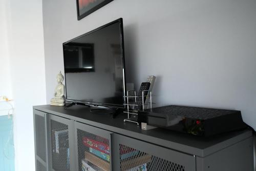 Elle comprend une télévision à écran plat installée au-dessus d'une commode. dans l'établissement Chez Maïse - CR CONCIERGERIE, à Dunkerque