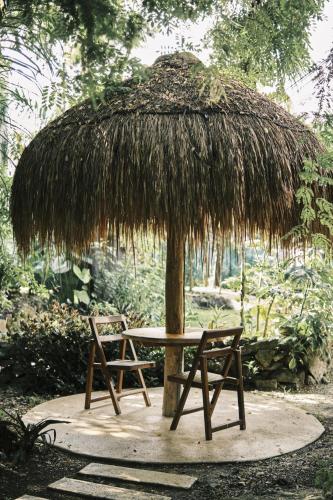 a table and two chairs under a straw umbrella at Villas Zamna - Jungle Villas in Cozumel