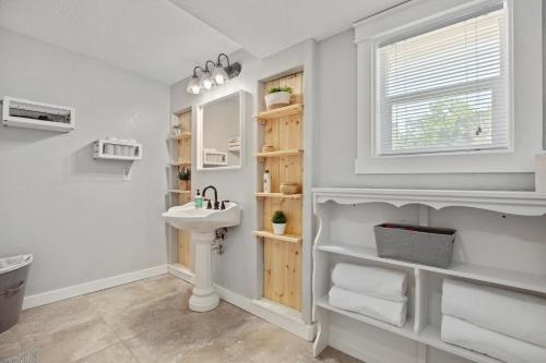 baño blanco con lavabo y ventana en Downtown Studio 1 at Beer Ranch Project Inn, en Wimberley