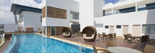 a swimming pool in a building with tables and chairs at Lux 3BR Suite Puteri Harbour Near Legoland & Hello Kitty with Water Views in Nusajaya