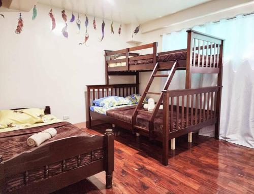 two bunk beds in a room with wooden floors at City Oasis: Steps Away from Urban Buzz in Baguio