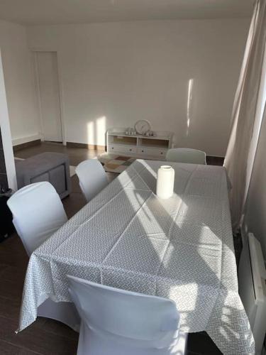 einen Tisch und weiße Stühle in einem Zimmer in der Unterkunft Le Pinky Bird - Maisons Alfort in Maisons-Alfort