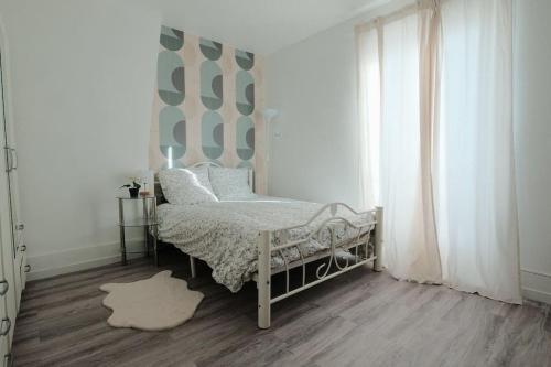 Schlafzimmer mit einem Bett und einem Fenster in der Unterkunft Le Pinky Bird - Maisons Alfort in Maisons-Alfort