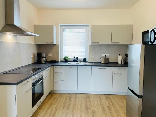 a kitchen with white cabinets and a white refrigerator at LIGHTPLACE - Moderne Apartments in Braunschweig - Balkon - Netflix - Am Kanal in Braunschweig