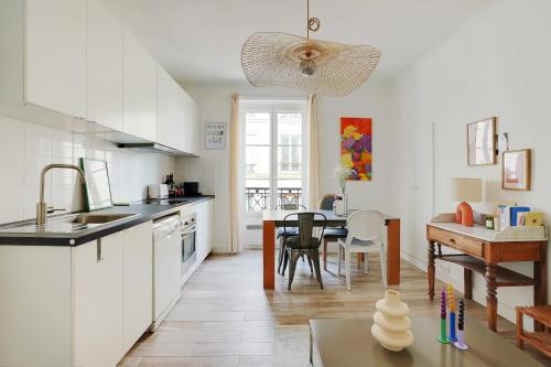 a kitchen with white cabinets and a dining room with a table at OBERKAMPF - BASTILLE Charming apartment in Paris