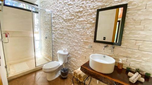 a bathroom with a sink and a toilet and a mirror at Villas Zamna - Jungle Villas in Cozumel